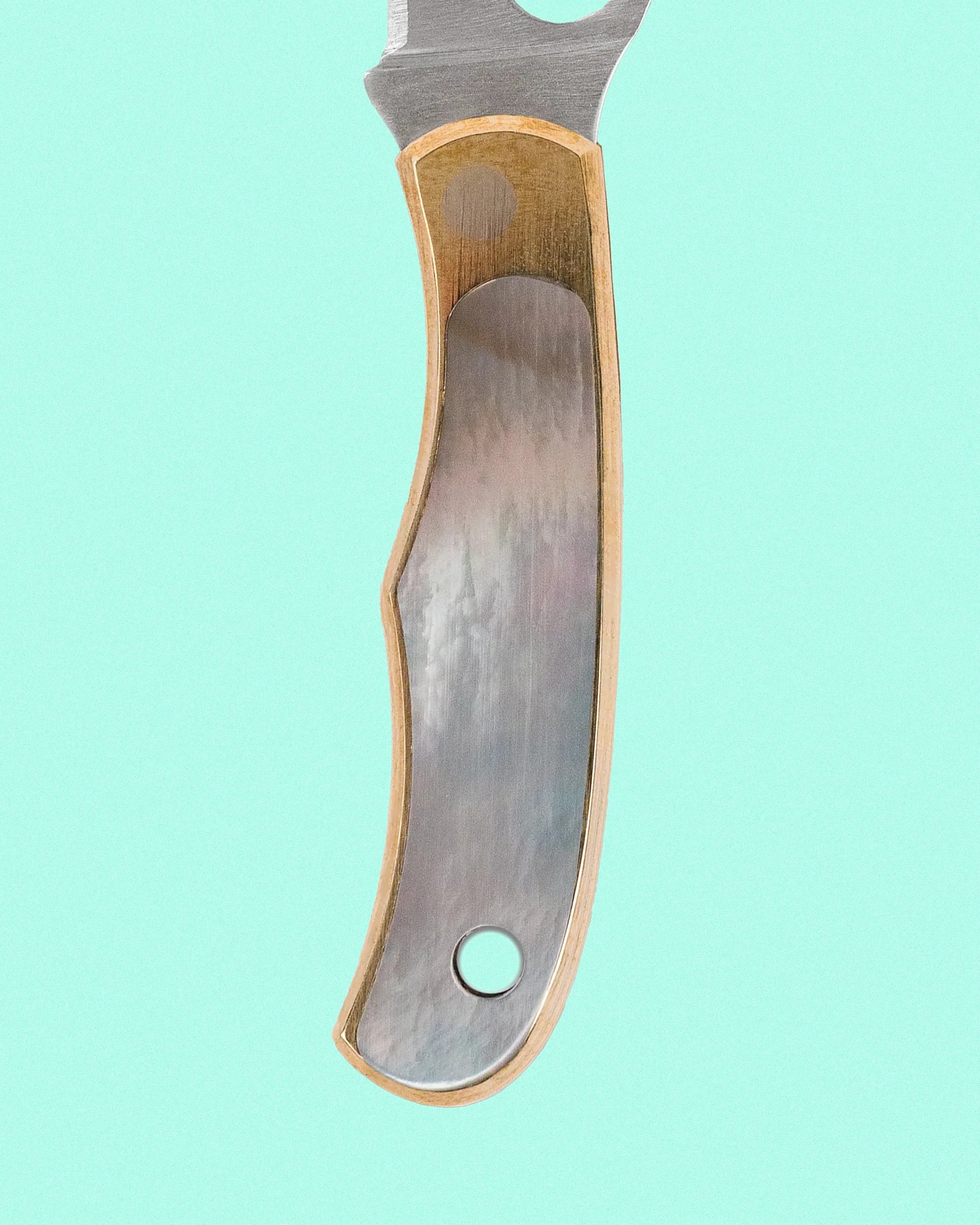 Handle of a knife with a metal inlay and wooden edges, featuring a circular hole near the bottom end, set against a light turquoise background.