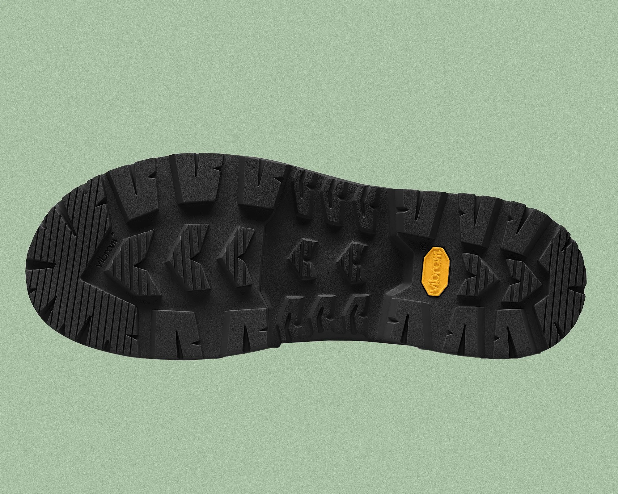 Black rubber shoe sole with deep, rugged treads designed for traction, featuring a yellow Vibram logo near the center.