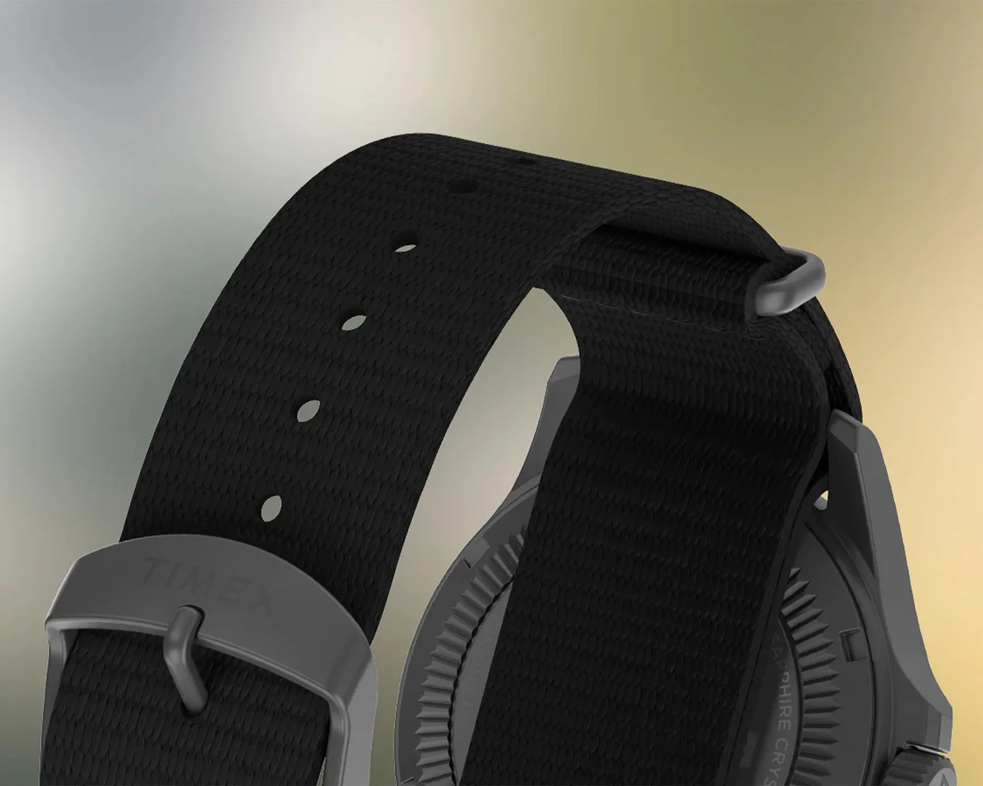 Black woven nylon watch strap with multiple adjustment holes and a matte gray metal buckle engraved with "TIMEX." The strap is attached to a dark gray watch case with a textured edge visible on the back.