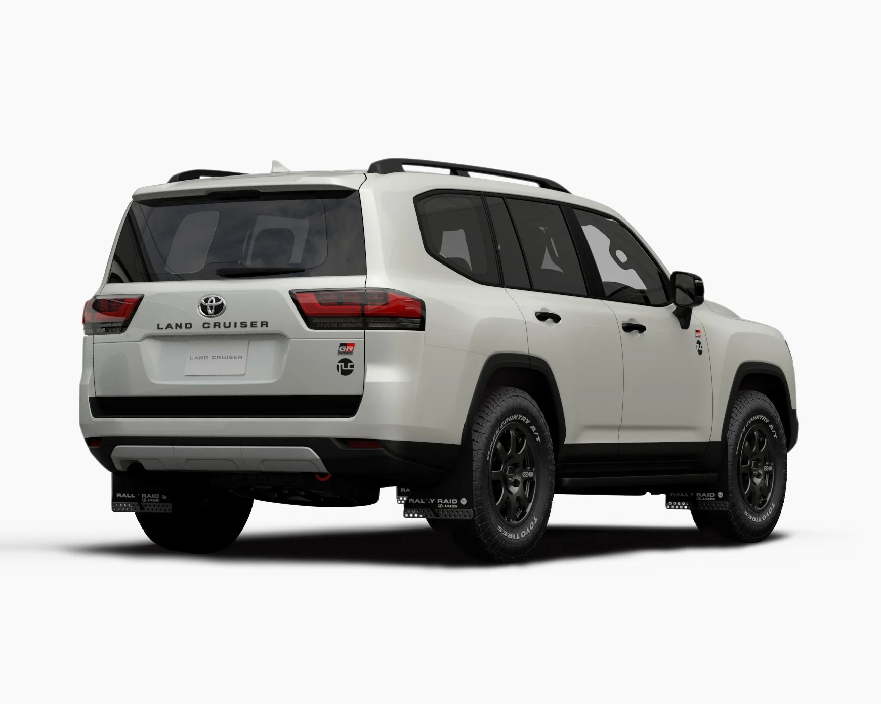 White Toyota Land Cruiser GR with black accents, black roof rails, and black off-road wheels with Toyo Open Country tires, viewed from the rear right side. The vehicle features tinted windows, a rear spoiler, and mud flaps labeled "Rally Raid." The "Land Cruiser" badge is centered on the rear, with the Toyota emblem above it and GR and other badges on the right side of the tailgate.