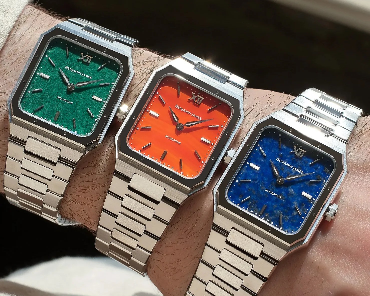 Three wristwatches with square stainless steel cases and matching metal link bracelets. Each watch has a distinctively colored dial: one green with a textured finish, one bright orange with a smooth finish, and one blue with a marbled finish. All dials feature silver hour markers, silver hands, and the brand name "BENJAMIN JAMES" along with the model name "SCARIFOUR" printed on them. The watches have a modern, angular design with a polished bezel and a crown on the right side.