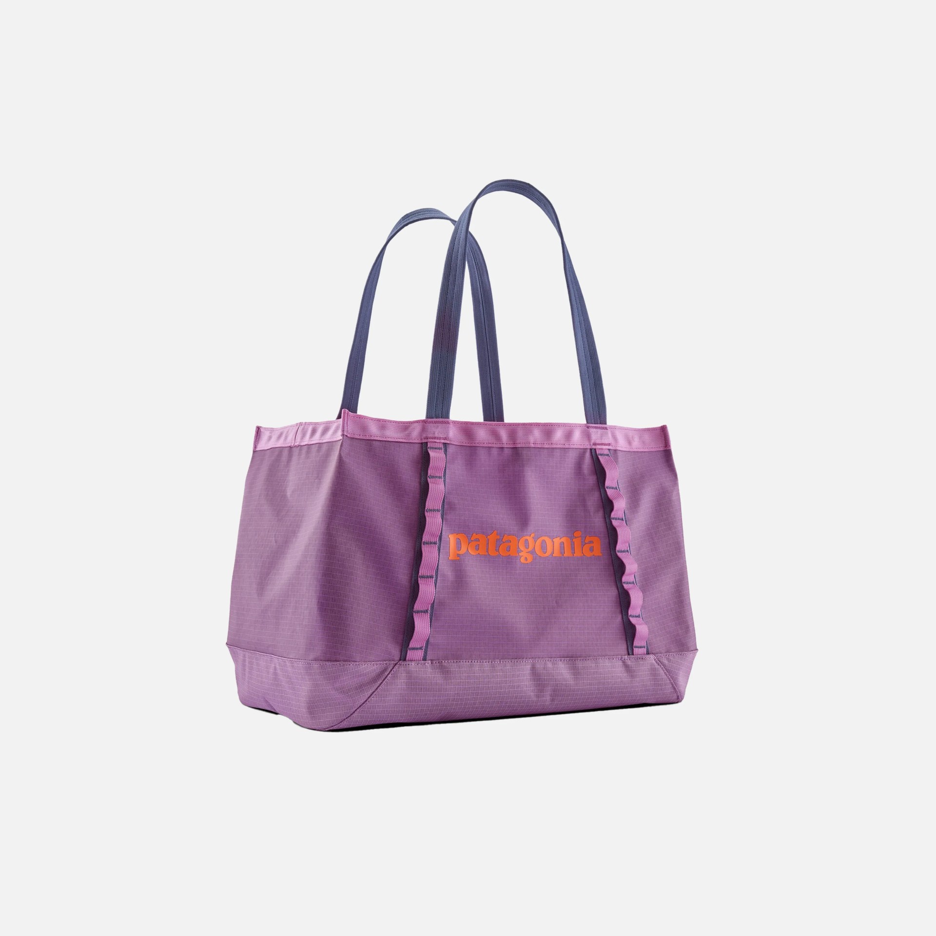 Purple Patagonia tote bag with two long dark blue handles, featuring the brand name "patagonia" in orange on the front. The bag has a rectangular base and vertical webbing loops on the front.