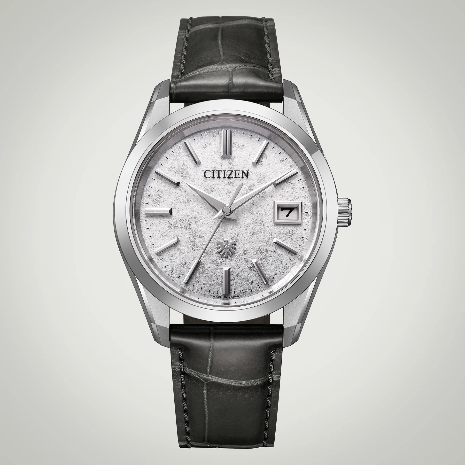 Silver Citizen wristwatch with a textured white dial, silver hour markers, and hands. It features a date window at the 3 o'clock position and a black leather strap with visible stitching. The watch has a polished stainless steel case.