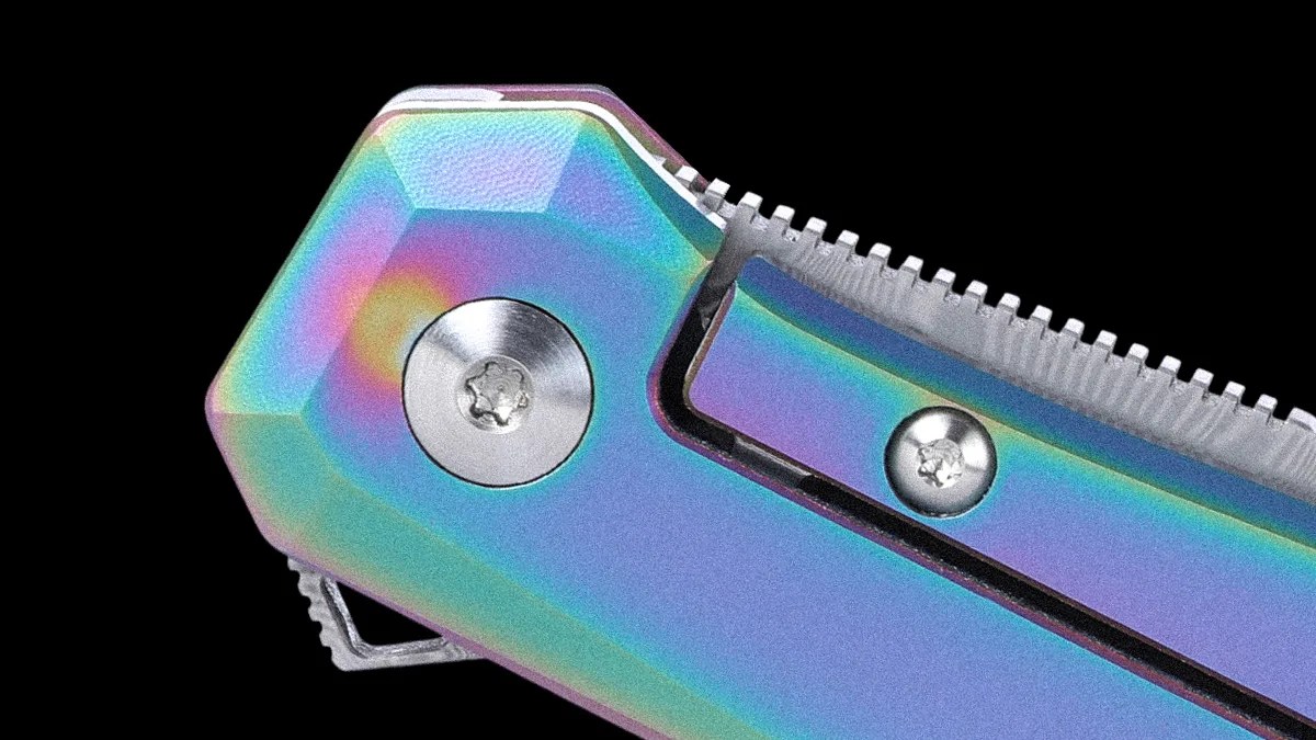 Close-up of a metallic object with a rainbow-colored, iridescent finish, featuring two silver screws and a textured edge, set against a black background.