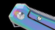 Close-up of a metallic object with a rainbow-colored, iridescent finish, featuring two silver screws and a textured edge, set against a black background.