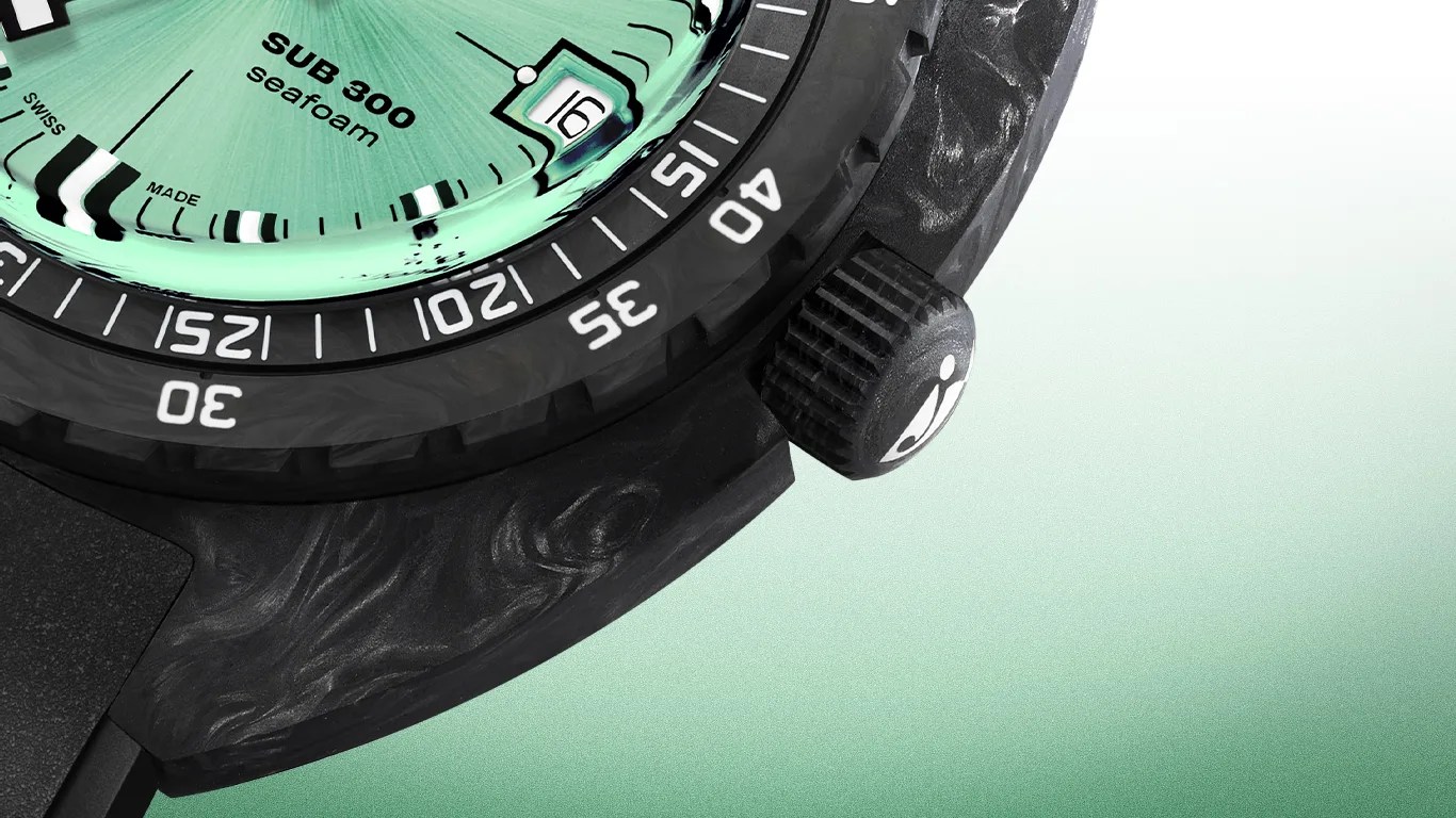 Close-up of a black Doxa dive watch with a textured bezel and crown, featuring a mint green dial labeled "SUB 300 seafoam" with a date window showing the number 16. The bezel has white numerals and markings for diving time. The watch case has a marbled pattern.
