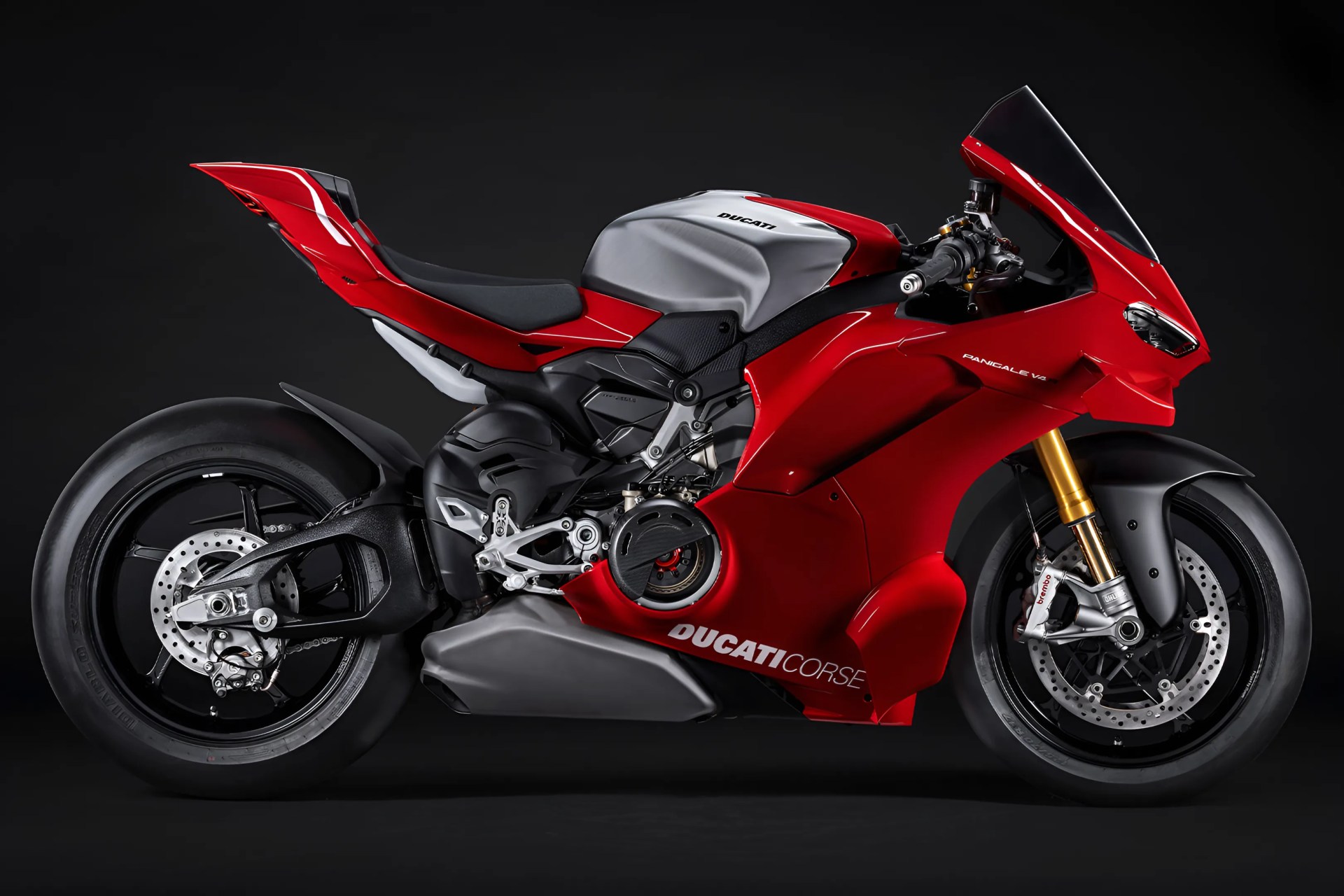 Red and silver Ducati Panigale V4 motorcycle with black wheels and gold front forks, shown in profile against a black background. The bike features aerodynamic fairings, a single seat, and "DUCATI CORSE" branding on the lower fairing.