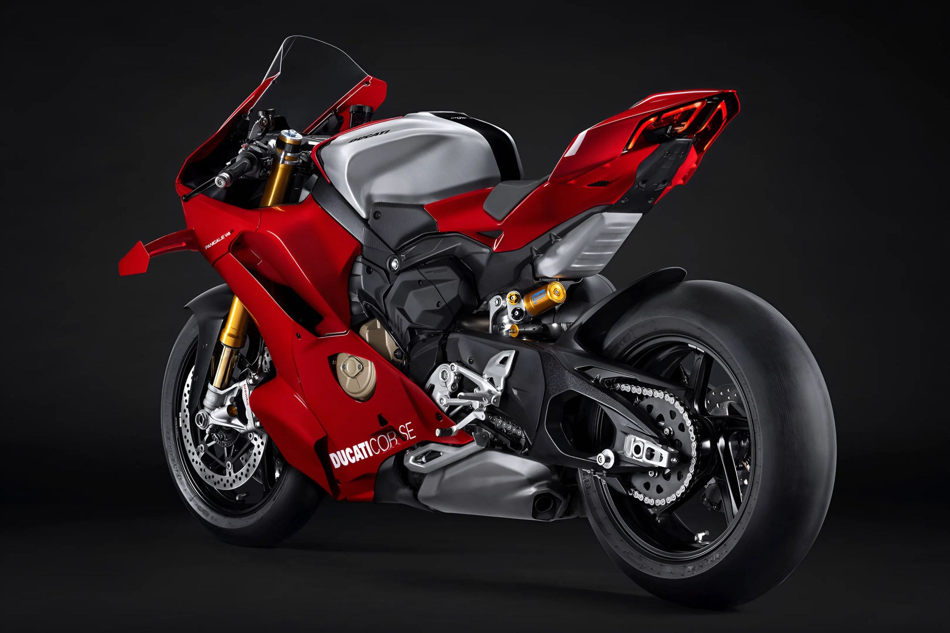 Red and silver Ducati sport motorcycle with black tires and gold suspension components, shown from the rear side on a black background. The bike features aerodynamic fairings and a sleek, aggressive design.