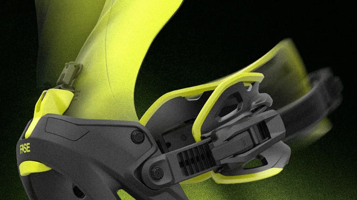 Close-up of a yellow and black ski or snowboard binding strap mechanism, showing the adjustable ratchet buckle in motion. The brand name "RAISE" is visible on the black part of the binding.