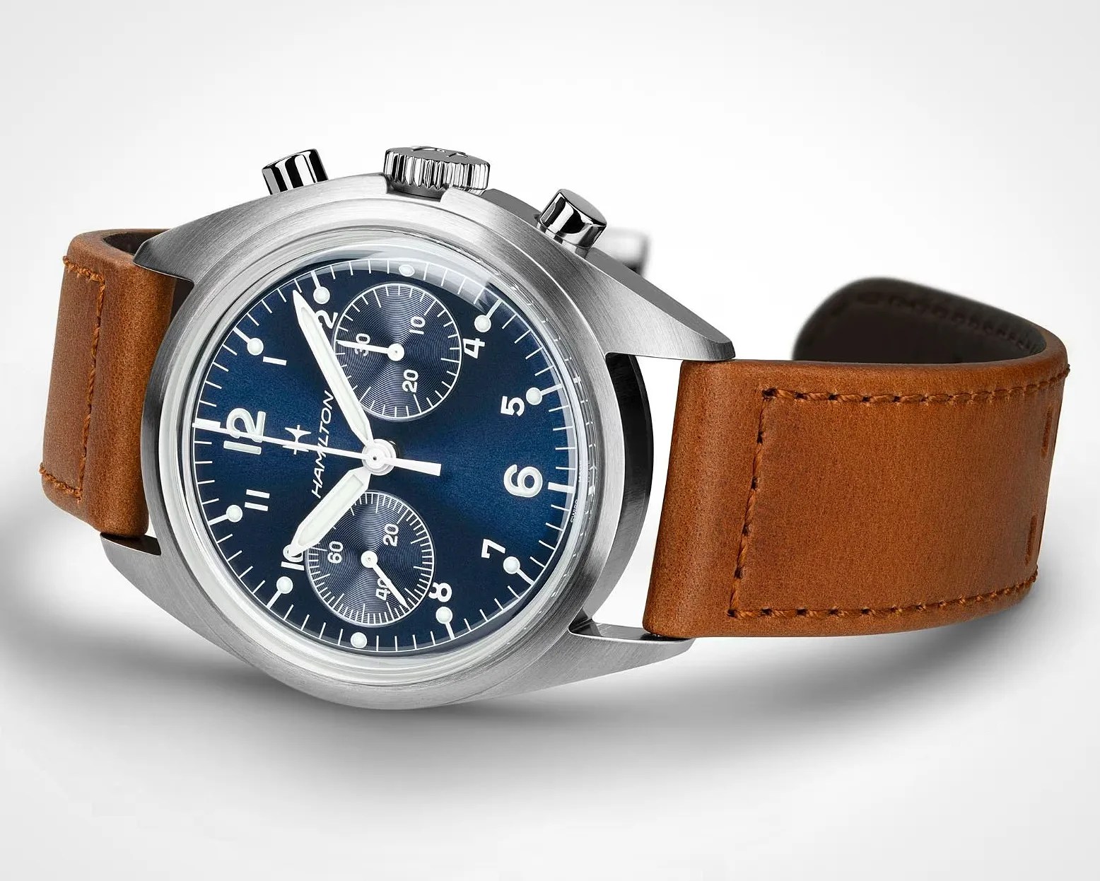 Stainless steel wristwatch with a deep blue dial featuring white numerals and markers, two subdials, and white hands. The watch has a brown leather strap with visible stitching and a brushed metal case with two push buttons and a crown. The brand name "Hamilton" is visible on the dial.