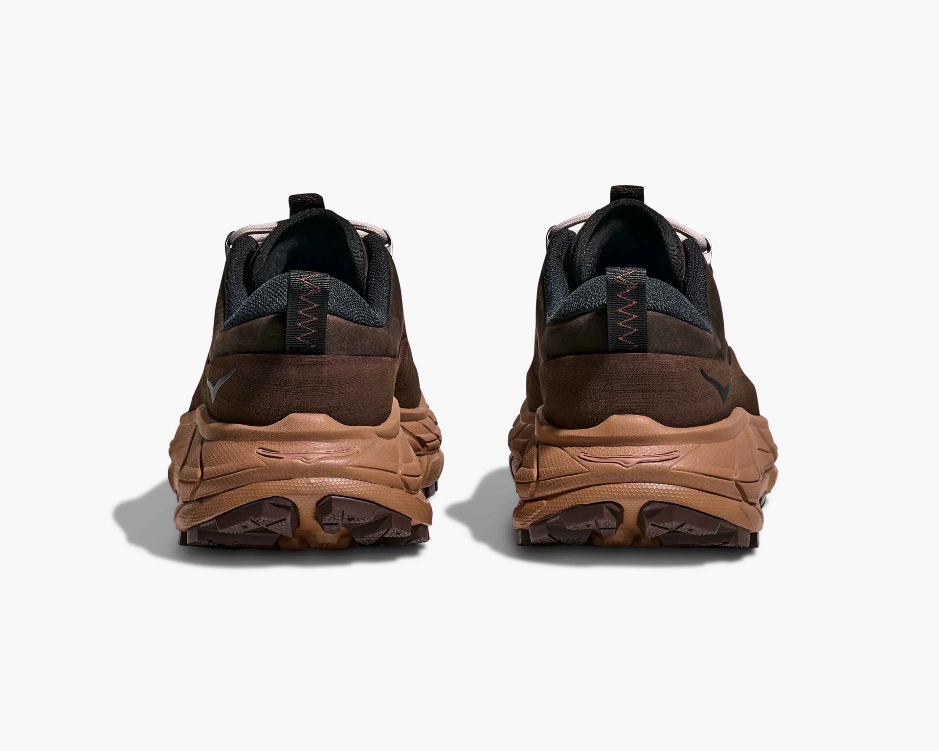 Pair of brown and black athletic shoes shown from the back, featuring thick, textured brown soles and black pull tabs with zigzag stitching on the heel. The upper part of the shoes is dark brown with black accents around the ankle collar.