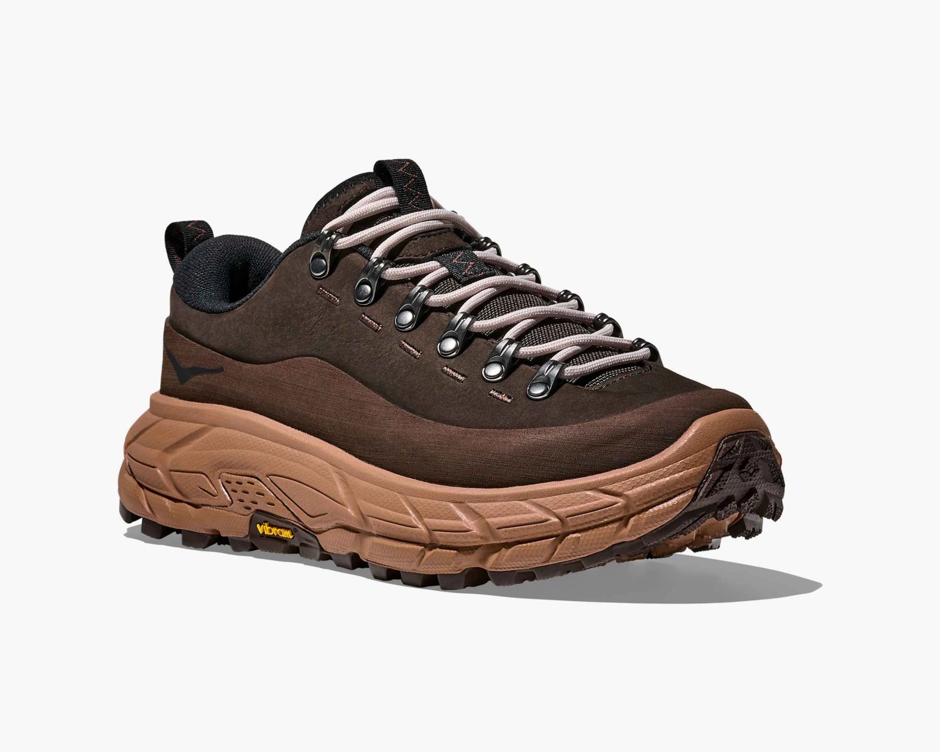 Brown hiking shoe with a thick, textured tan sole featuring Vibram branding. The upper is dark brown with metal eyelets and light beige laces. The shoe has a padded black collar and a pull tab at the heel and tongue. The design is rugged and suitable for outdoor activities.