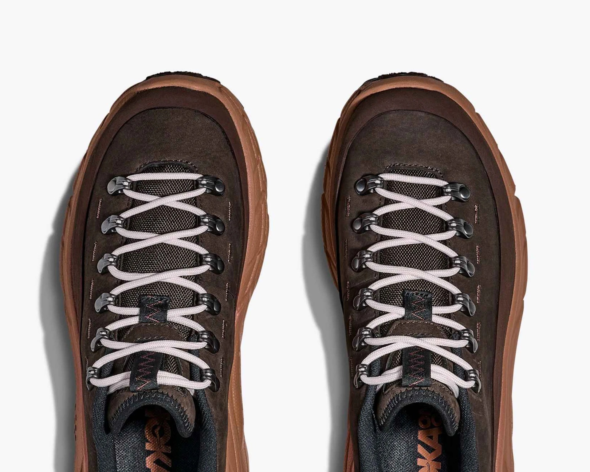 Pair of brown hiking shoes with light-colored laces threaded through metal eyelets, featuring a rugged sole and mesh tongue.