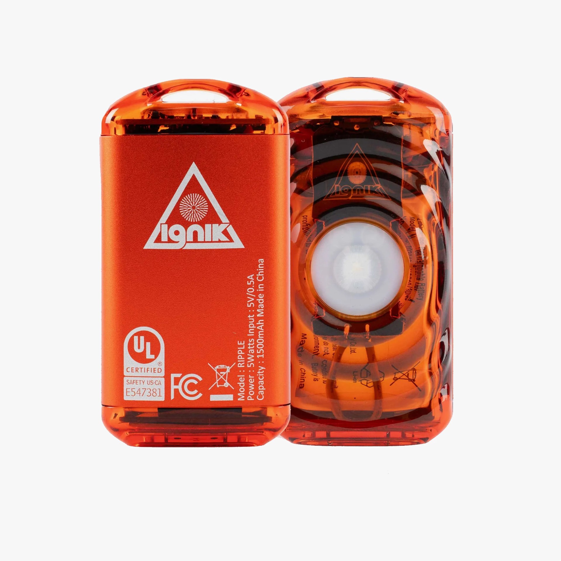 Two compact, rectangular orange devices with rounded edges and a translucent top section. One device shows the front with a white "Ignik" logo inside a triangle, certification marks, and technical specifications including model "RIPPLE," power input 5V/0.5A, and capacity 1500mAh. The other device shows the back with a circular light or sensor in the center, visible internal components, and the same logo faintly visible. Both have a small handle-like cutout at the top.