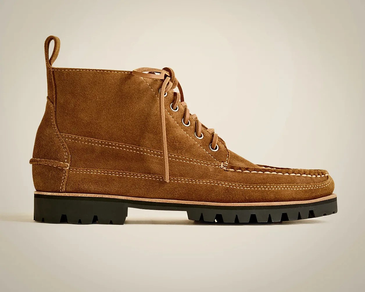 Brown suede lace-up ankle boot with a moc toe design, white stitching details, and a black lug sole. The boot features a pull tab at the back and metal eyelets for the laces.