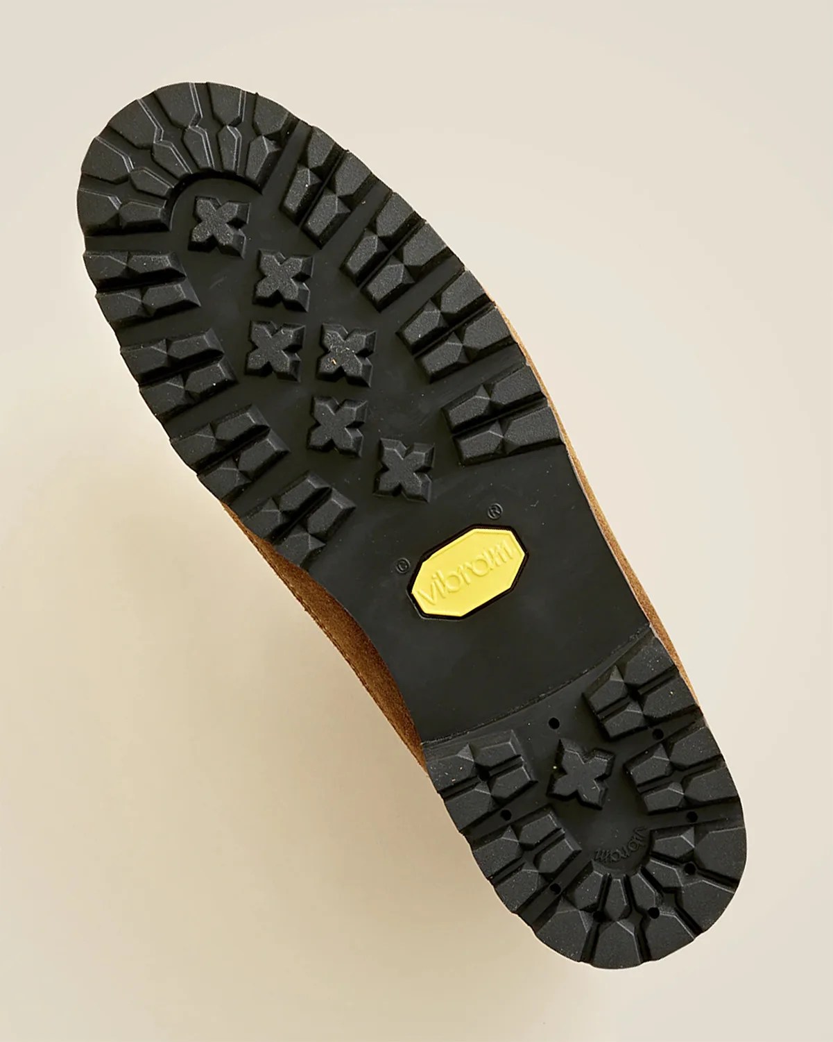 Sole of a brown shoe with a black Vibram rubber outsole featuring deep treads and a yellow Vibram logo in the center.