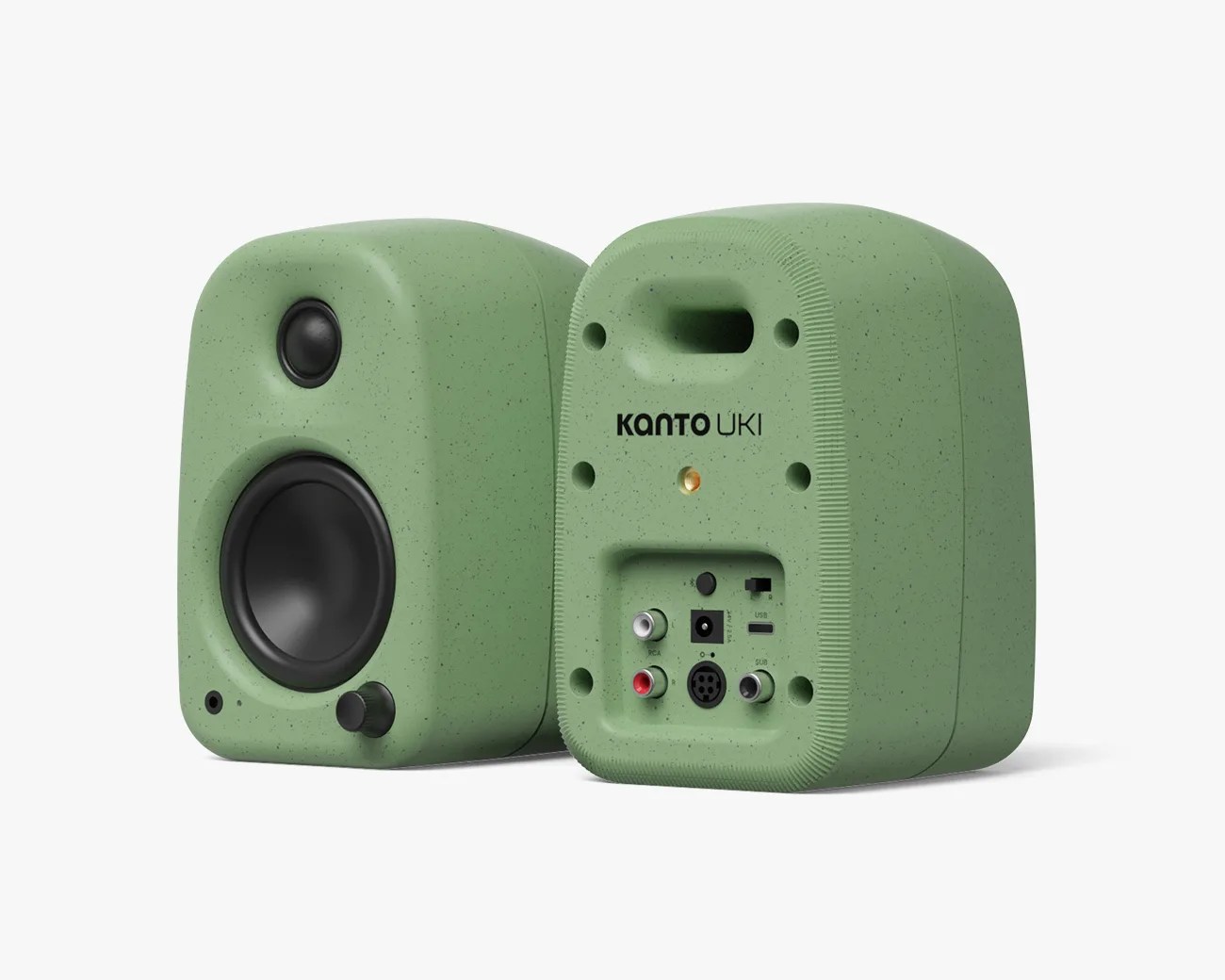 Two green Kanto Uki speakers with a speckled finish are shown. The front speaker features a tweeter, a woofer, a volume knob, and a headphone jack. The rear speaker displays various input ports including RCA, USB, power, and subwoofer connections, along with the Kanto Uki branding. The speakers have a rounded, compact design.