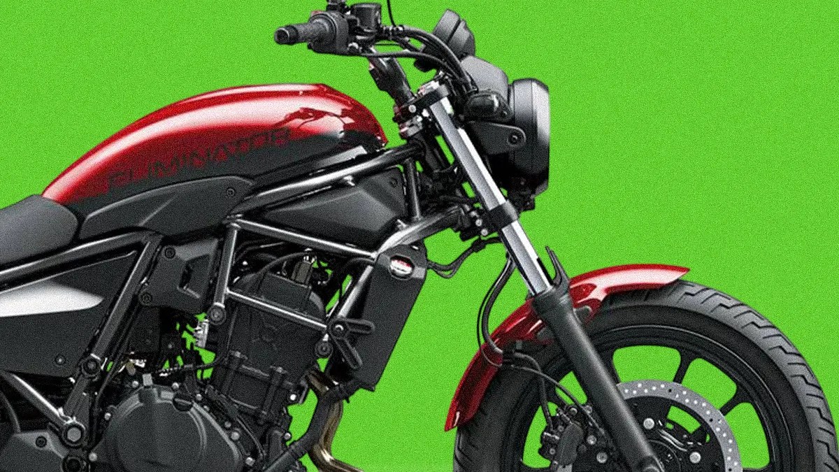 Close-up of the front and middle section of a red and black motorcycle, showing the fuel tank, handlebars, front suspension, and front wheel with disc brake against a green background.