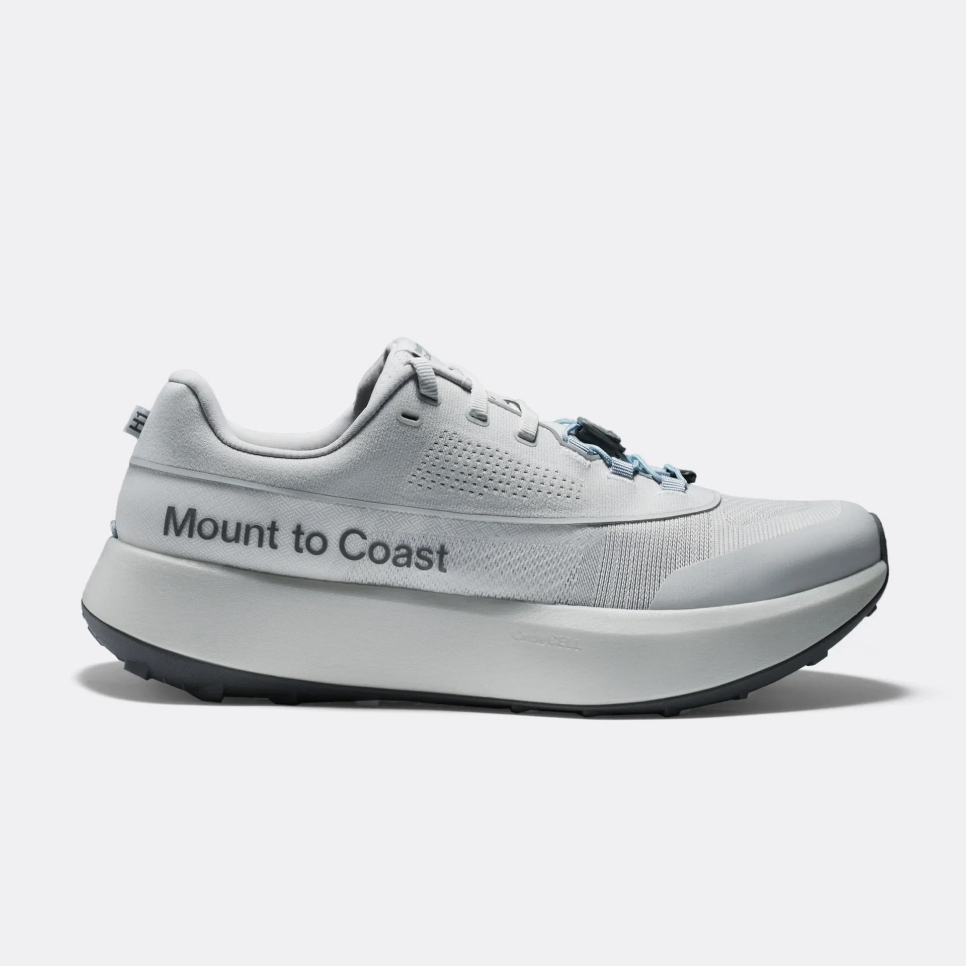 Light gray athletic shoe with a thick white sole and black outsole. The side of the shoe features the text "Mount to Coast" in dark gray. The shoe has a sleek design with perforations near the laces and a reinforced toe area. The laces include a black and blue adjustment mechanism.