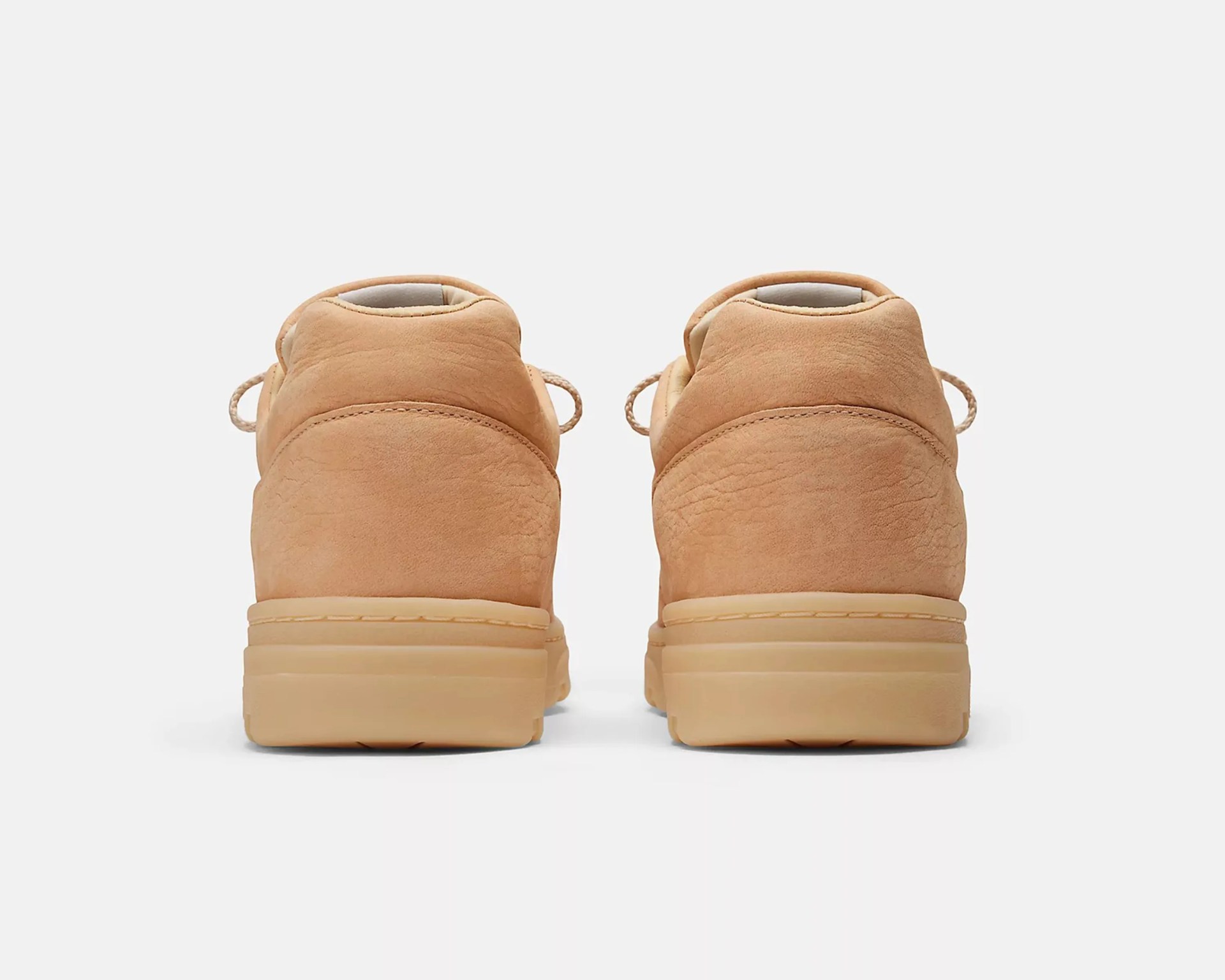 Pair of tan suede sneakers shown from the back, featuring a smooth, slightly textured upper and a thick, matching tan rubber sole. The shoes have a padded collar and visible stitching along the heel.