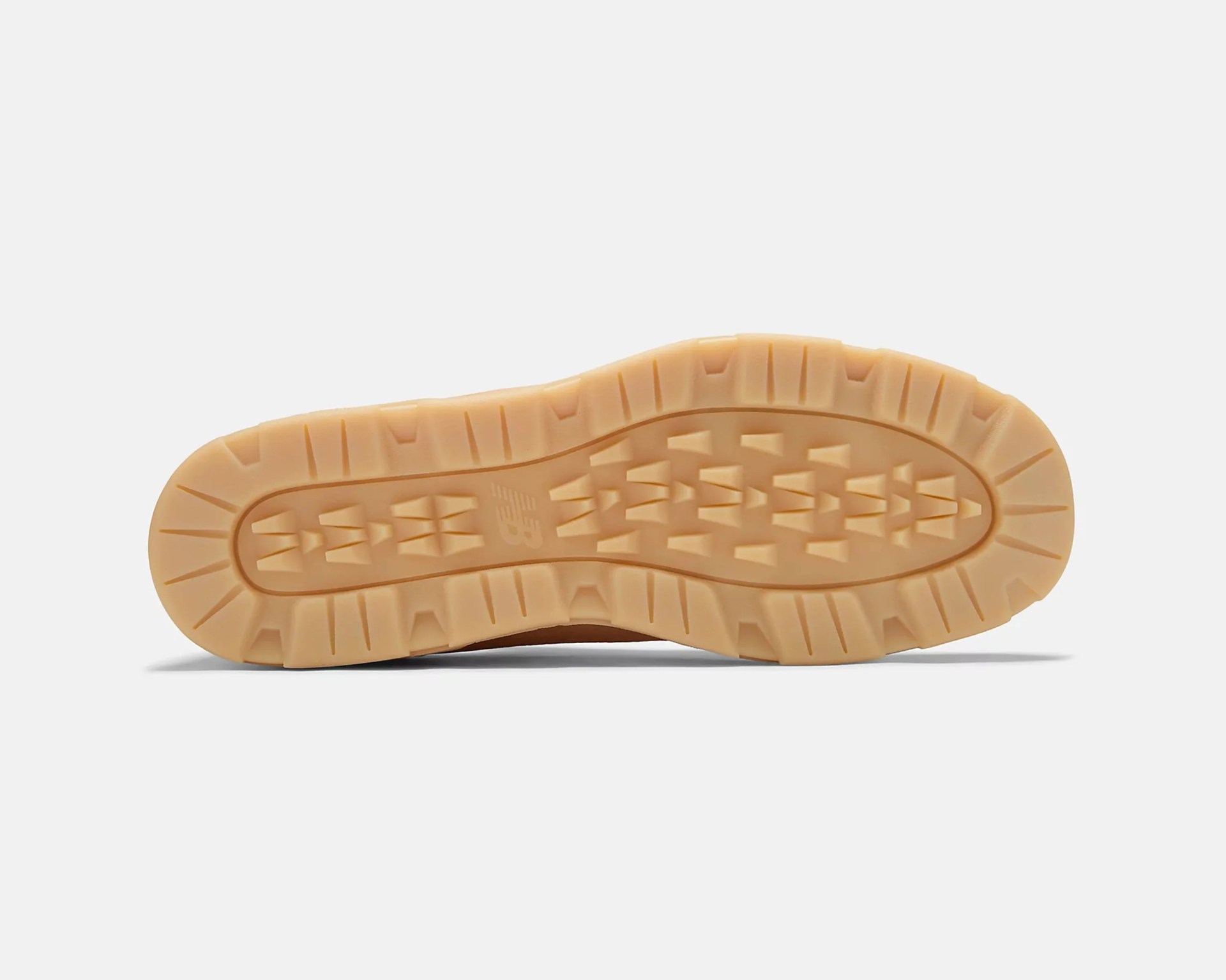 Light brown rubber outsole of a shoe with a textured tread pattern featuring rectangular and triangular shapes, and a small embossed "NB" logo near the center.