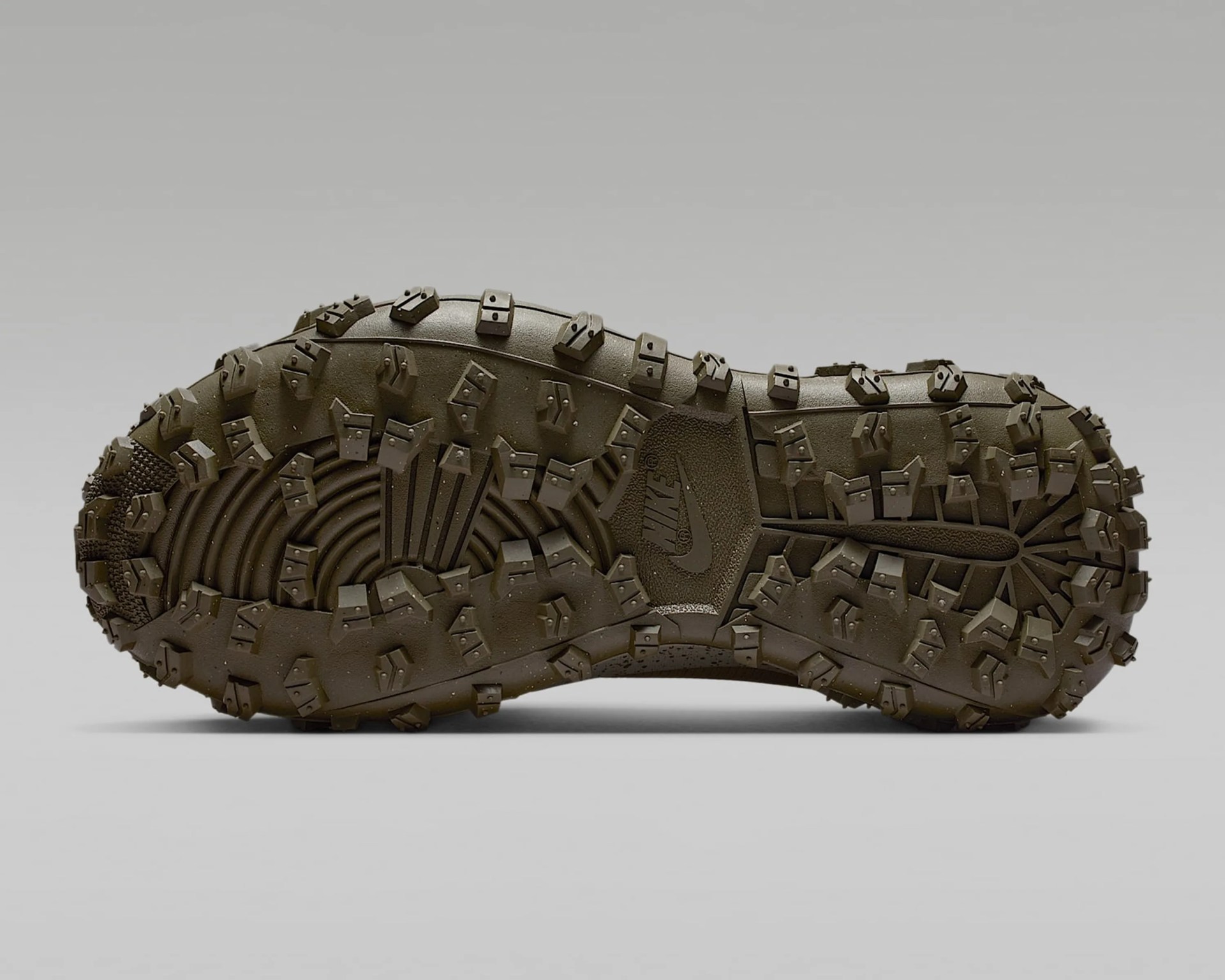 Sole of a Nike shoe with a rugged, heavily textured tread pattern designed for traction, featuring multiple angular lugs and a central Nike logo. The sole is dark brown and appears durable for outdoor or trail use.