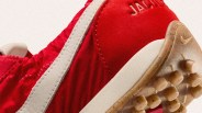 Close-up of the heel and sole of a red sneaker with a white stripe. The sole is translucent with small rubber studs and has a small Nike swoosh logo. The word "JACK" is partially visible on the red upper part of the shoe.