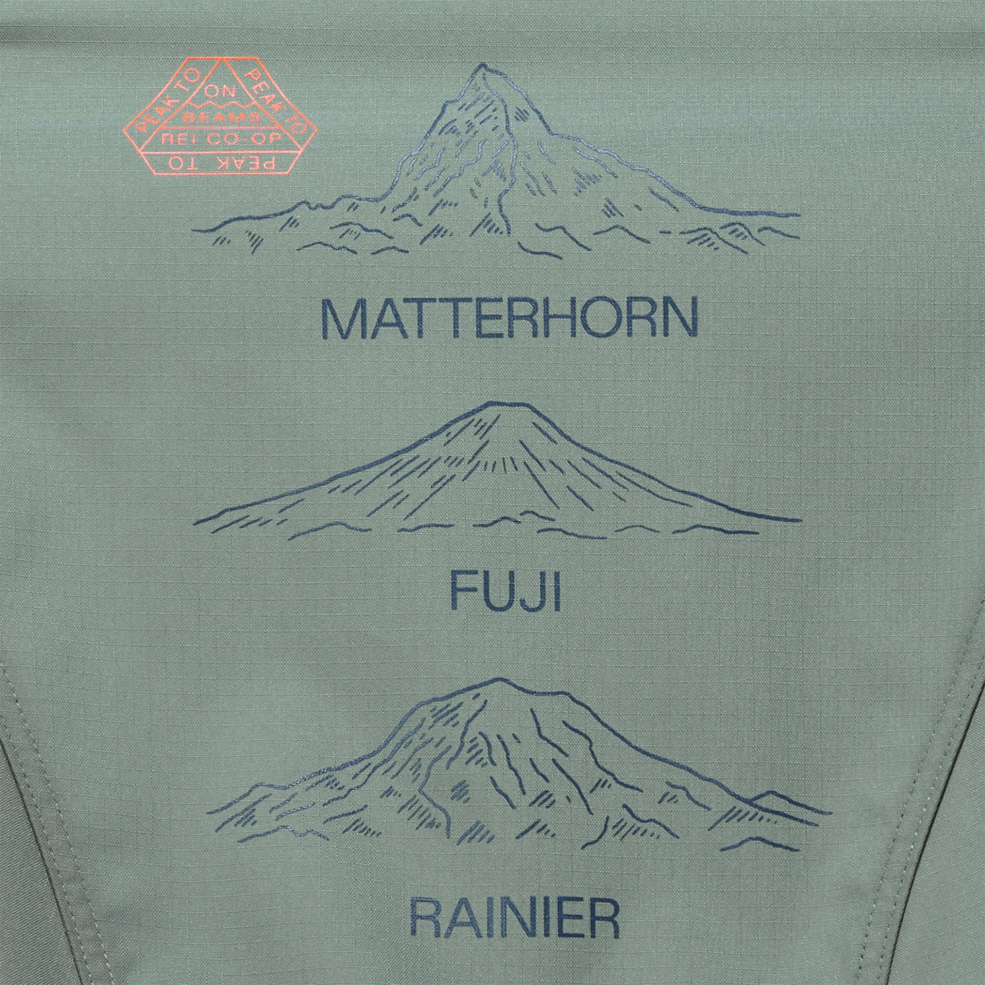 Illustrations of three mountains labeled "Matterhorn," "Fuji," and "Rainier" arranged vertically on a green fabric background. In the top left corner, there is a red hexagonal logo with the text "PEAK TO PEAK ON BEAMS REI CO-OP.