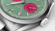 Close-up of a luxury wristwatch with a green textured dial, featuring white hour markers and hands. The dial includes a red power reserve indicator marked "POWER RESERVE" with numbers from 0 to 10, and a date window showing "28." The watch has a stainless steel case and crown engraved with "ORIS." The dial also displays the text "BIG CROWN 10 DAYS" and "SWISS MADE.