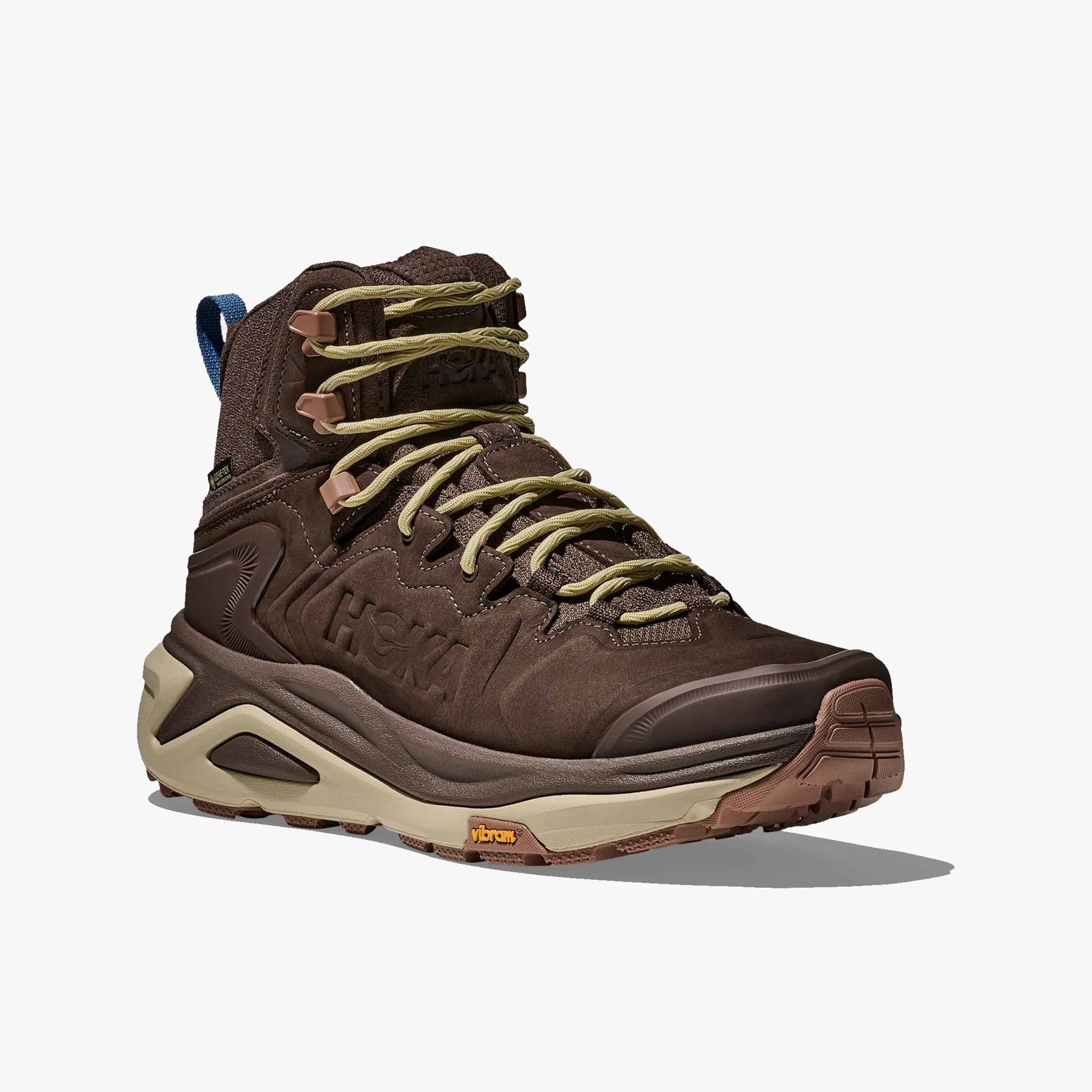 Brown high-top hiking shoe with beige laces, a thick beige and brown sole, and a blue pull tab at the back. The shoe features embossed branding on the side and a Vibram logo on the sole.