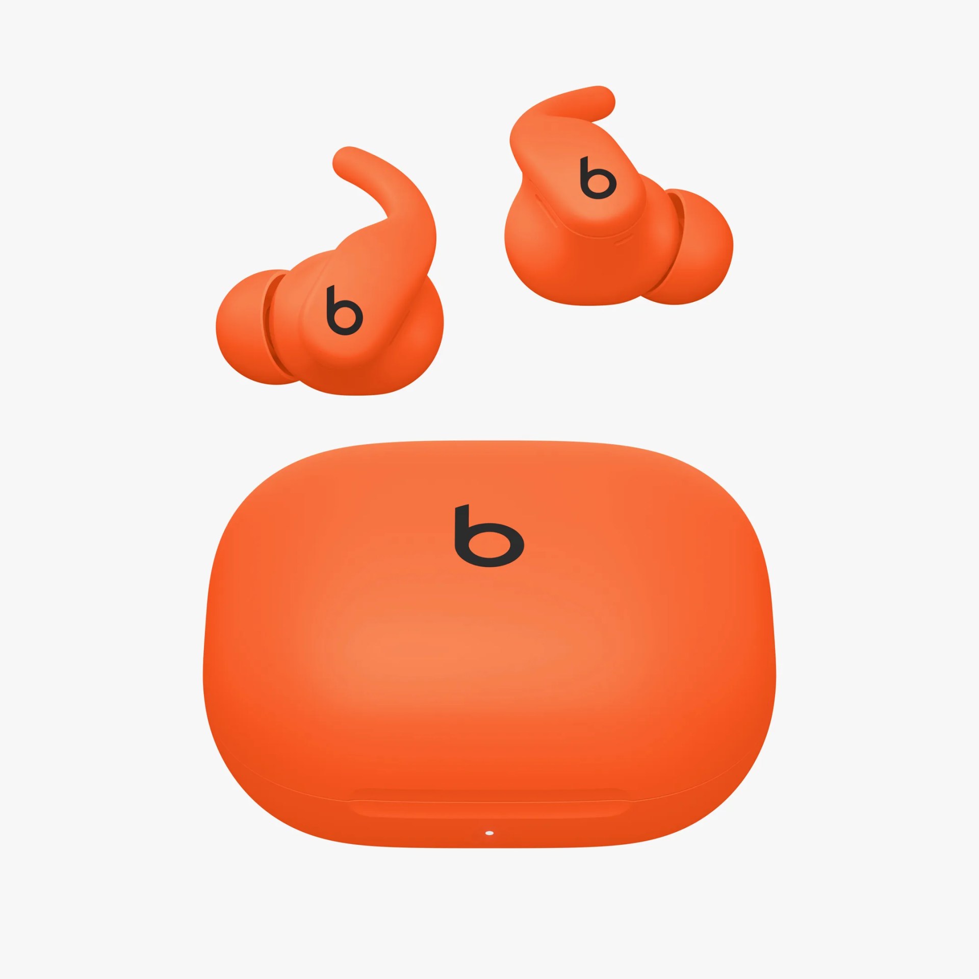 Orange wireless earbuds with a matching charging case, each earbud featuring a small hook for secure fit and a black "b" logo on the outer surface. The charging case is rounded rectangular with a black "b" logo on top and a small indicator light on the front.