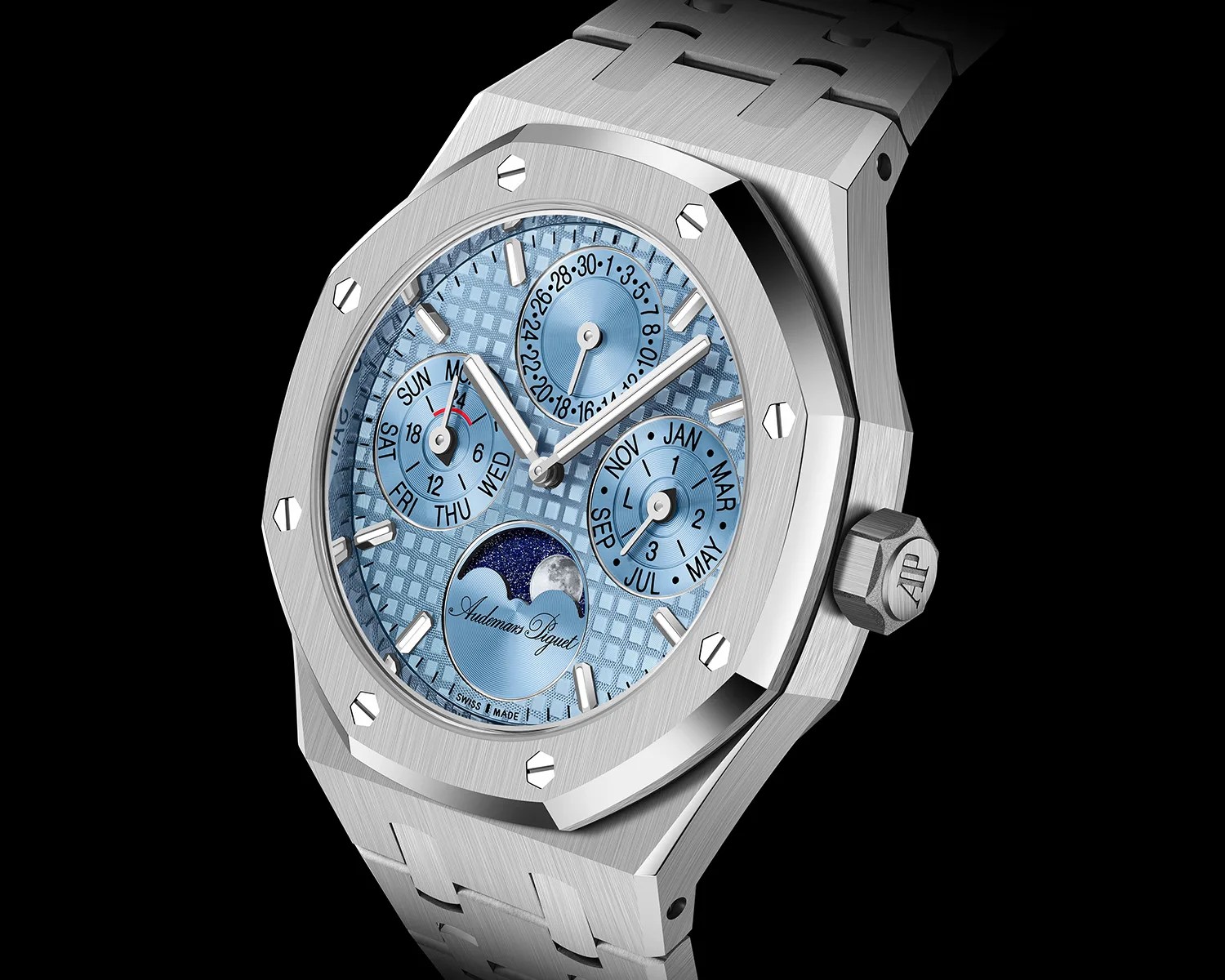 Silver Audemars Piguet wristwatch with a light blue textured dial featuring three subdials for day, date, and month, and a moon phase indicator at the 6 o'clock position. The watch has a brushed metal octagonal bezel secured with screws and a matching metal bracelet. The crown is engraved with the "AP" logo.