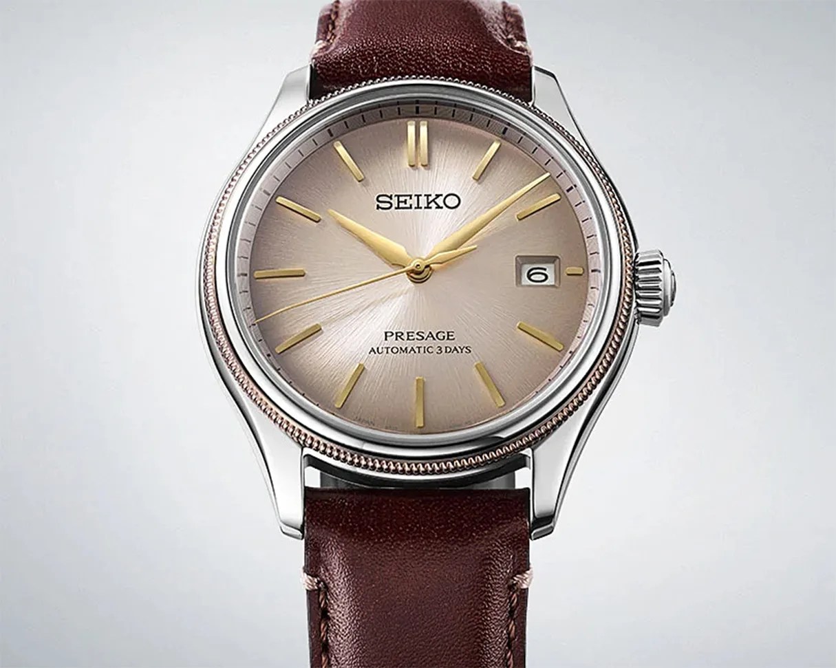 Seiko Presage wristwatch with a round silver dial featuring gold hour markers and hands. The watch has a date window at the 3 o'clock position and a brown leather strap. The bezel is silver with a textured edge, and the dial includes the text "SEIKO," "PRESAGE," and "AUTOMATIC 3 DAYS.