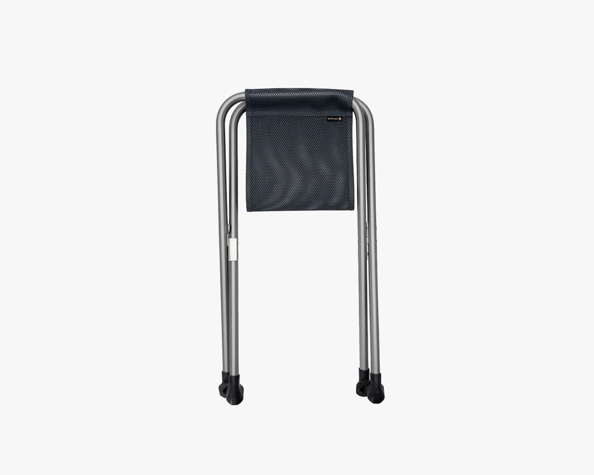 Compact, foldable stool with a silver metal frame and a black mesh fabric seat. The stool is shown in its folded position, with four black rubber feet at the bottom of the legs for stability.