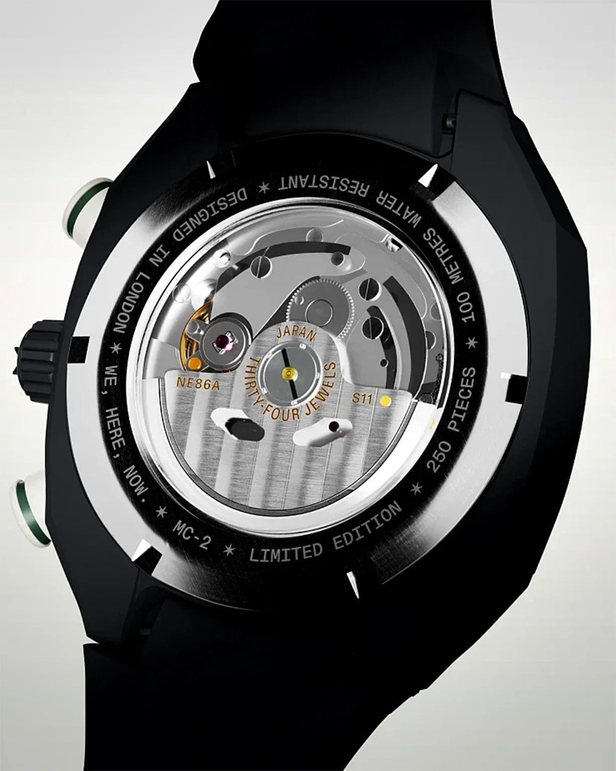 Back view of a black wristwatch showcasing its mechanical movement through a transparent case back. The visible mechanism includes gears and jewels, with inscriptions such as "JAPAN," "THIRTY-FOUR JEWELS," "NE86A," and "S11." The outer rim of the case back is engraved with details including "DESIGNED IN LONDON," "WATER RESISTANT 100 METRES," "LIMITED EDITION," and "250 PIECES." The watch has a black strap and two pushers with green accents.