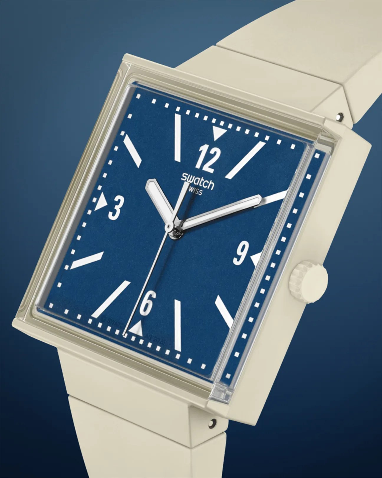 Square wristwatch with a beige strap and case, featuring a blue dial. The dial has white hour markers, including numerals at 12, 3, 6, and 9, and white hour, minute, and second hands. The brand name "Swatch" is printed below the 12 o'clock marker.