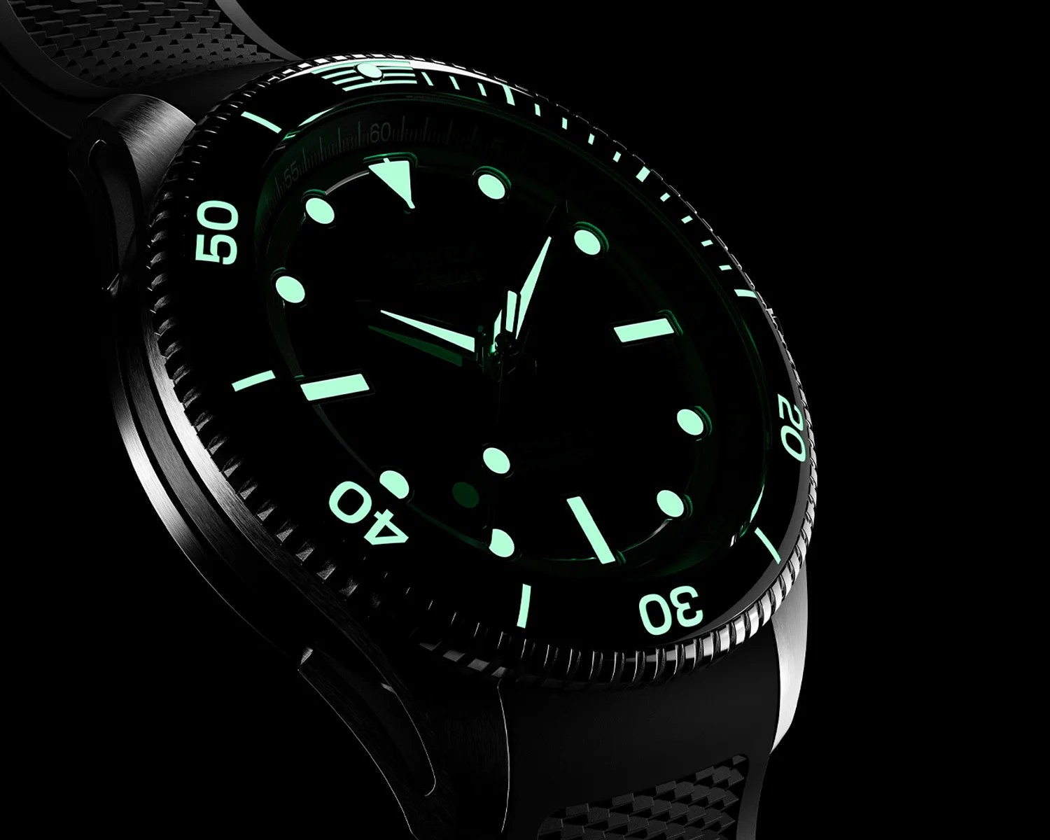 Close-up of a black dive watch with luminous markers and hands glowing green in the dark. The watch features a rotating bezel with minute markings, a textured rubber strap, and a brushed metal case. The time displayed is approximately 10:10.