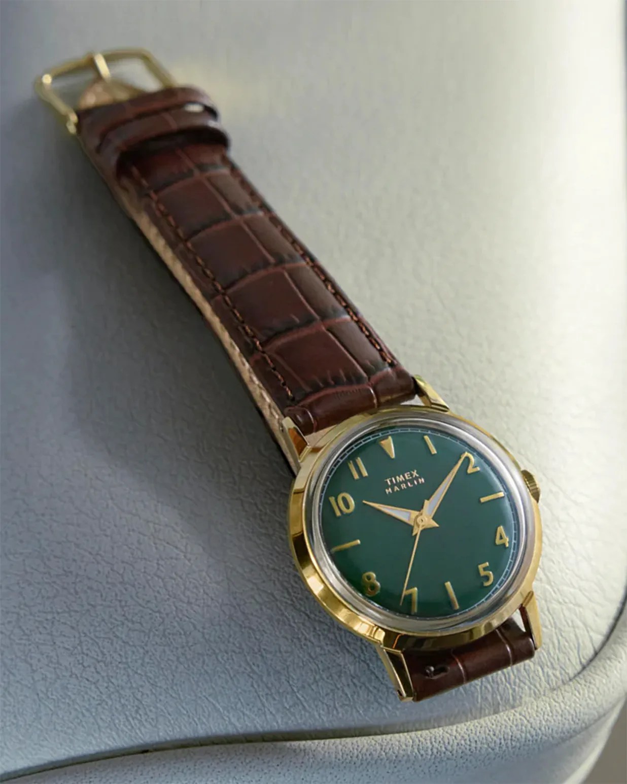 Gold-toned Timex Marlin wristwatch with a green dial, gold numerals and hands, and a brown leather strap featuring a crocodile pattern.
