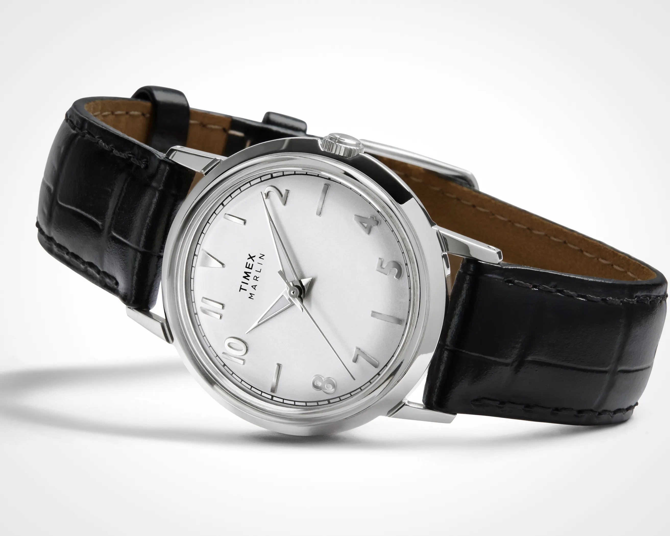 Timex Marlin wristwatch with a silver round dial, silver hour markers, and silver hands, featuring a black leather strap with a crocodile pattern and a silver buckle.