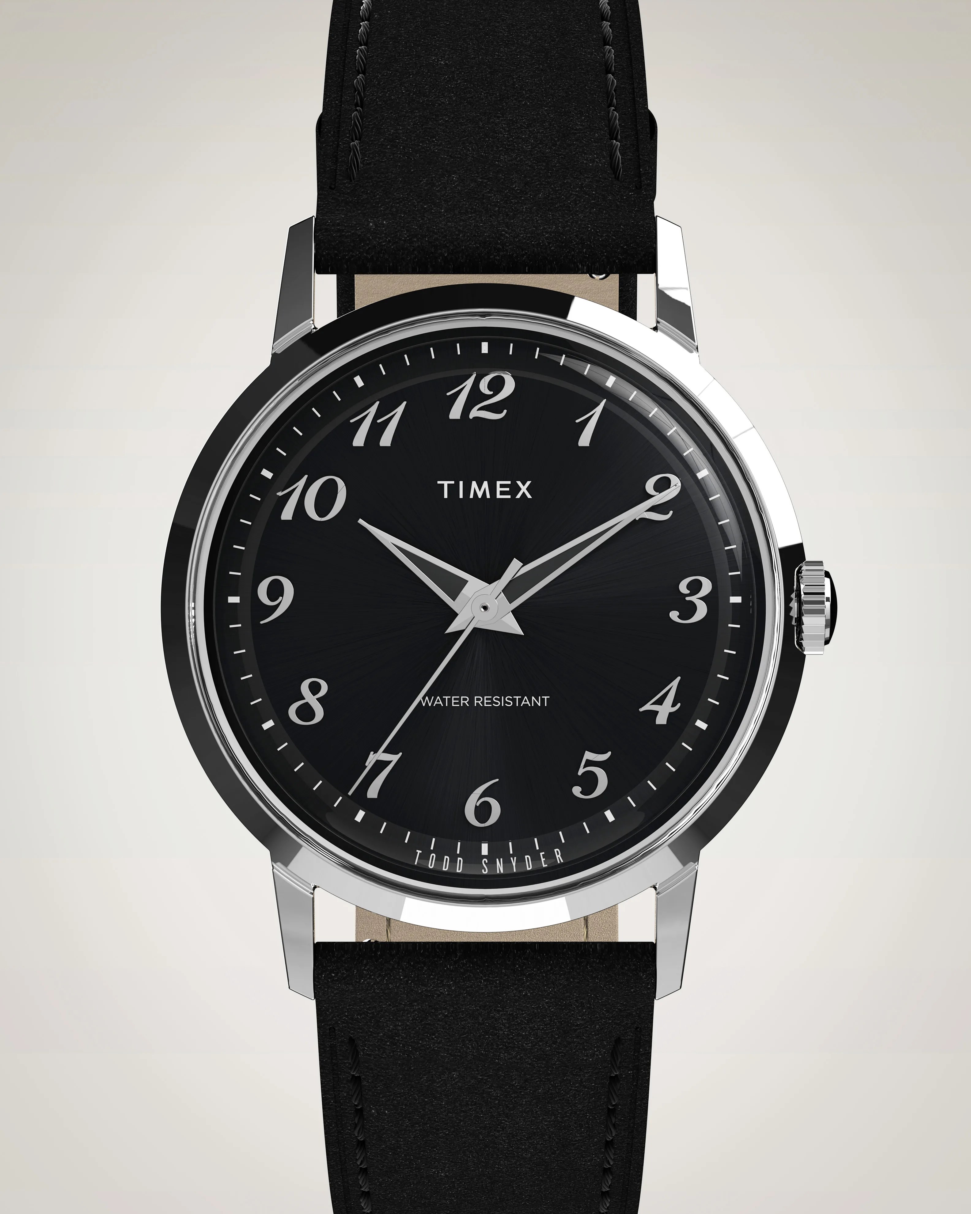 Black Timex wristwatch with a silver round case, black dial, and silver Arabic numerals. The watch has three silver hands and a black leather strap with visible stitching. The dial features the text "TIMEX," "WATER RESISTANT," and "TODD SNYDER" near the bottom.