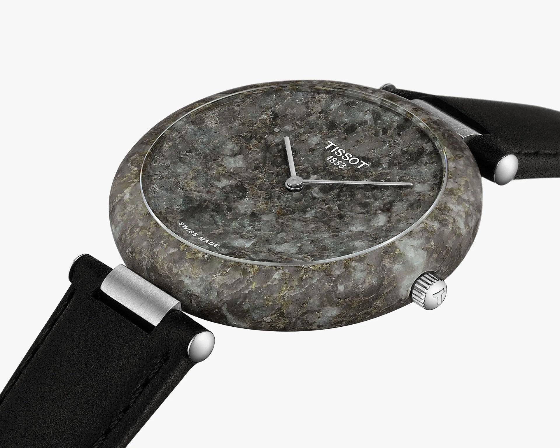 Round wristwatch with a textured stone-like gray dial and case, featuring silver hour and minute hands. The watch face displays the brand name "TISSOT 1853" and "SWISS MADE" at the bottom. It has a black leather strap with silver connectors and a silver crown with a "T" logo.