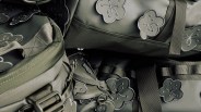 Close-up of olive green fabric bags featuring embroidered flower patches and sturdy straps with detailed stitching.