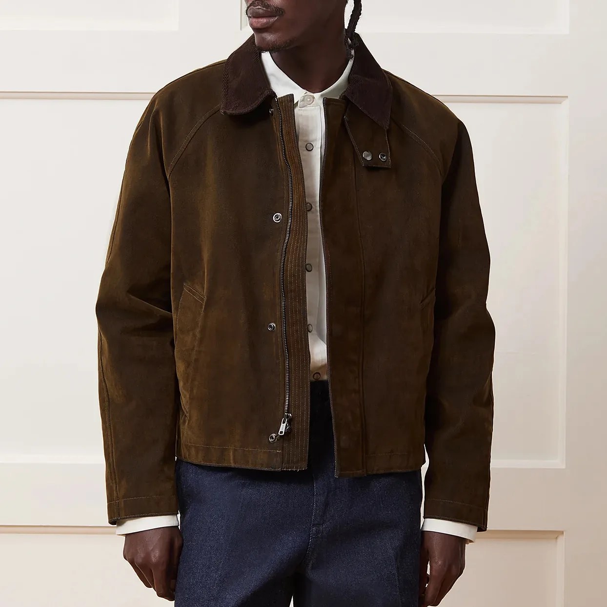 Brown suede jacket with a dark brown corduroy collar, front zipper, and snap button closures, worn over a white button-up shirt and paired with dark blue pants.