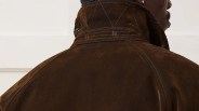 Close-up of the back of a dark brown corduroy jacket with detailed stitching on the collar and shoulder seams. The collar is turned up, showing reinforced stitching patterns and metal snap buttons. The fabric has a soft, textured appearance.