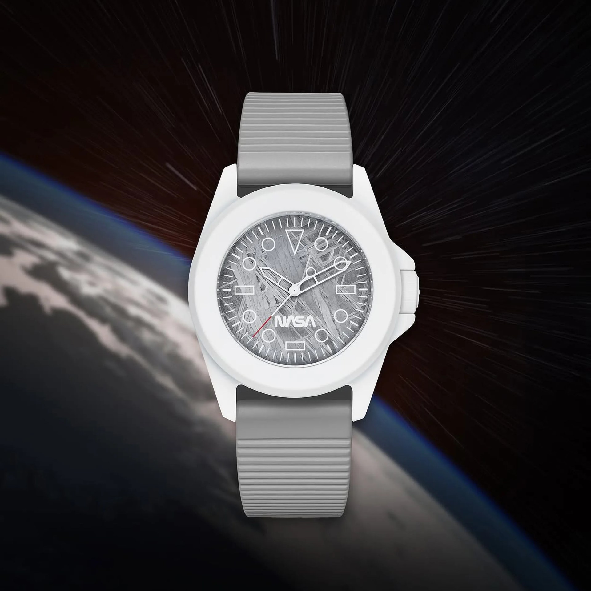 White wristwatch with a gray textured dial featuring the NASA logo, white hour markers, and hands, and a red second hand. The watch has a gray ribbed strap and is set against a space background showing Earth and star trails.