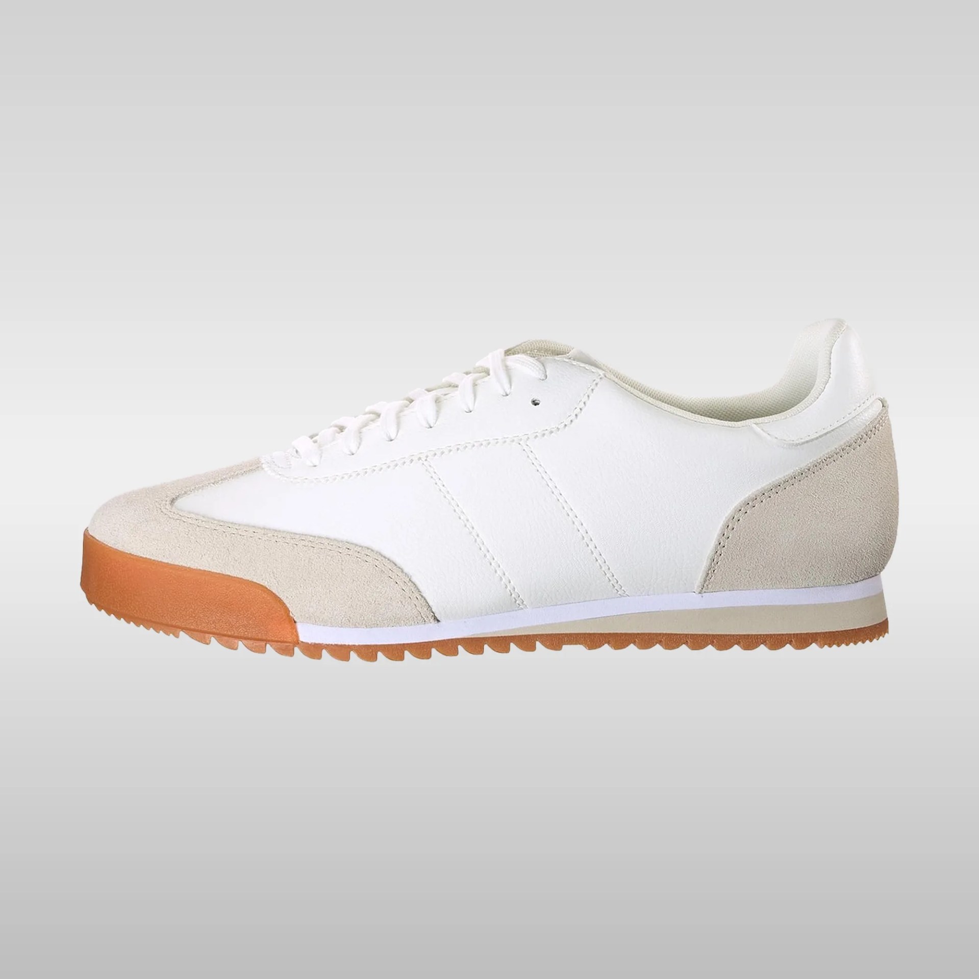 White low-top sneaker with beige suede accents on the toe and heel, white laces, and a gum rubber sole with a ridged pattern. The upper is primarily smooth white leather with subtle stitching details.