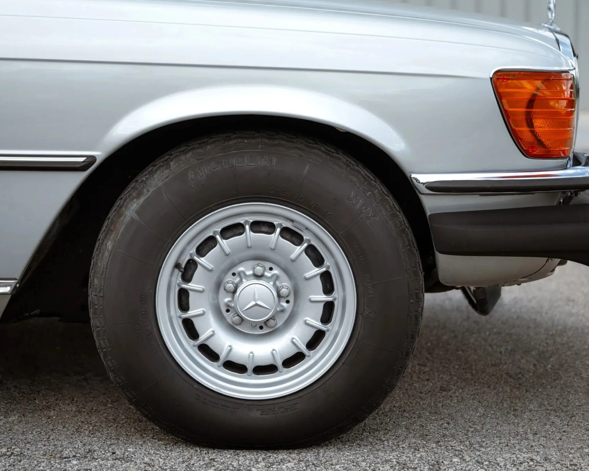 Close-up of a silver Mercedes-Benz car wheel with Michelin tire on asphalt.