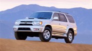 Silver Toyota 4Runner SUV parked on a dirt hill with mountains in the background.