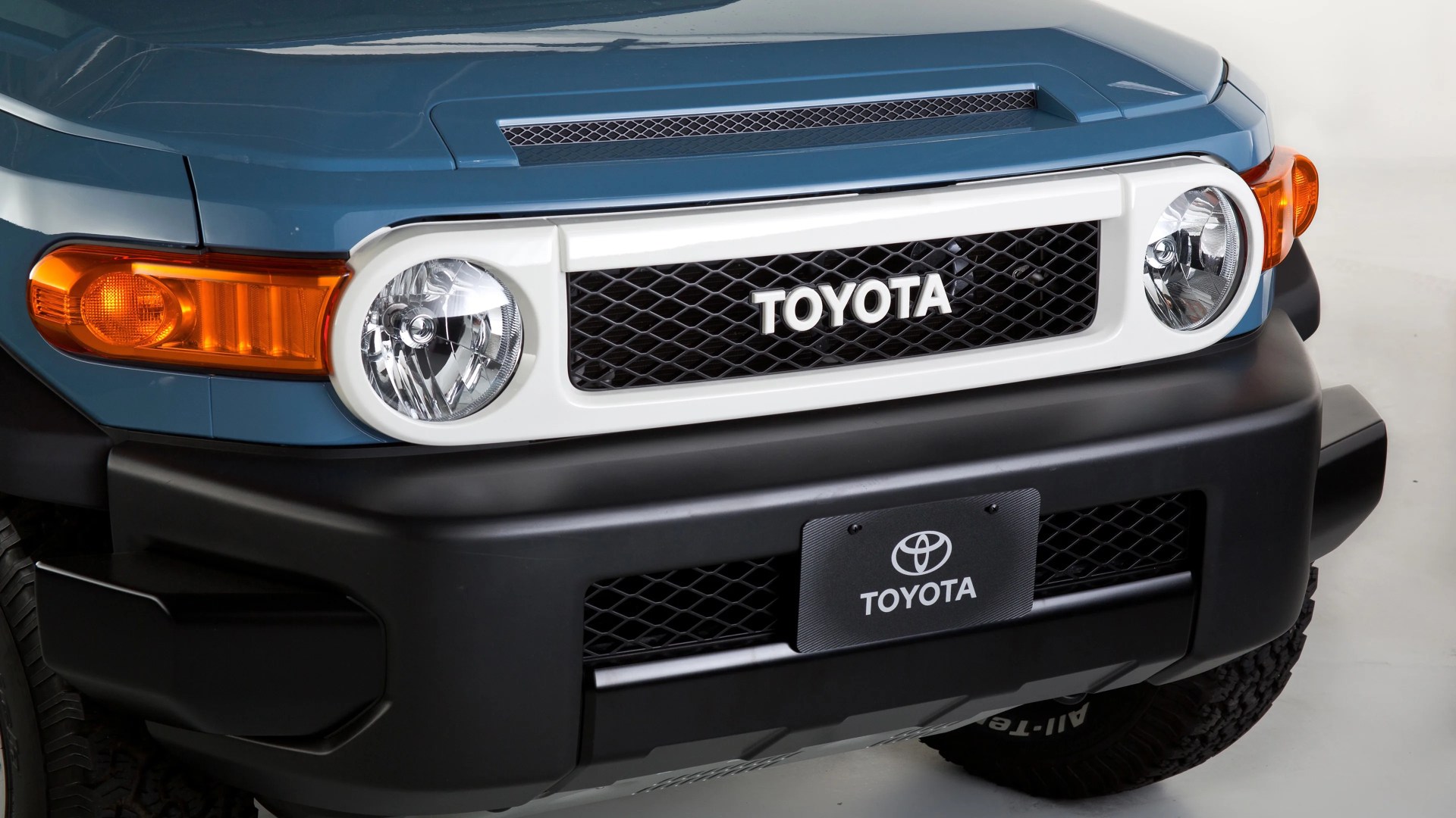 Front grille of a blue Toyota vehicle with round headlights and a black bumper.