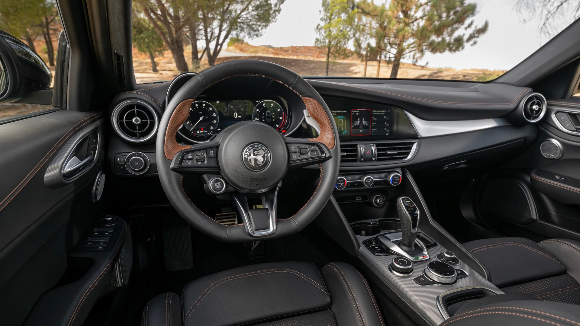 Interior view of an Alfa Romeo car showing a black leather steering wheel with brown accents, digital dashboard, and center console with gear shifter and control knobs.